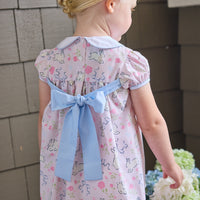 Little English traditional children's clothing. Classic peter pan dress with capped sleeves and a light blue sash in a light pink bunny print for little girls. Easter outfit for girls.