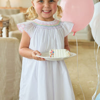 Little English traditional children's clothing. White flutter sleeve dress for toddler girls with rainbow smocking at the collar. Birthday dress for little girls