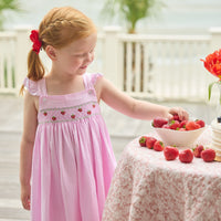 Little English traditional children's clothing. Light pink seersucker gingham dress for little girls with flutter sleeves and strawberry smocking across the chest