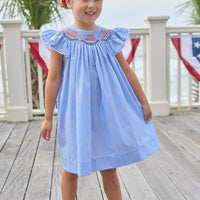 Little English traditional children's clothing. Flutter sleeve dress for toddler girls in royal blue mini gingham with smocking at the collar and American flag bunting