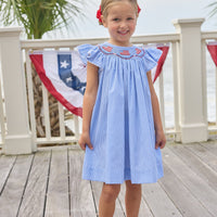 Little English traditional children's clothing. Flutter sleeve dress for toddler girls in royal blue mini gingham with smocking at the collar and American flag bunting