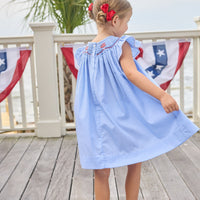 Little English traditional children's clothing. Flutter sleeve dress for toddler girls in royal blue mini gingham with smocking at the collar and American flag bunting