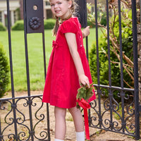 Little English traditional children's clothing. Red corduroy dress with capped sleeves and off-center fixed bow at waist. Holiday dress for little girls.