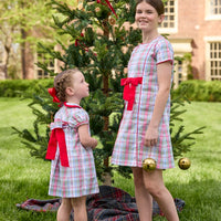 Little English classic children's clothing. Girls A-line dress in red and green plaid with red bow and red piping detail for the holidays. Matching toddler girl dress with ruffled peter pan collar and bow tie sash in back.