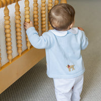 Little English traditional baby clothes, signature white cotton playsuit with peter pan collar, light blue picot trim, and crochet lab. Accompanied by a crochet cardigan with lab motif on sides and back for baby boy.
