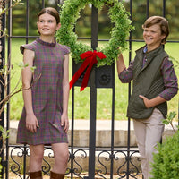Little English traditional children's clothing. Olive and maroon Thornhill Plaid column dress with capped sleeves, ruffled neckline, and fixed bow in back for older girls for the holidays. Boys Button Down Shirt in Thornhill Plaid with Classic Quilted Vest in Olive layered over top. Paired with Classic Pant in tan Stone Corduroy.