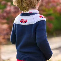 Little English traditional children's clothing. Navy crew neck sweater with red fire truck fair isle detail. Layered over white knit turtleneck with all-over fire truck print. Paired with red corduroy banded pants. Fall outfit for toddler boys.