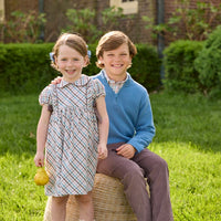 Little English traditional children's clothing. Boys stormy blue quarter zip sweater layered over blue, pink, and brown Wilmington Plaid button down shirt and paired with chocolate brown corduroy classic pants. Short sleeve peter pan dress in blue, pink, and brown Wilmington Plaid with brown corduroy details for little girls.