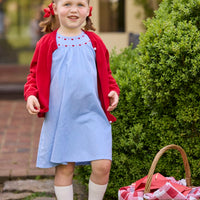 Little English traditional children's clothing. Soft blue chambray short sleeve dress for little girls with red and pink heart embroidery around the neckline. Red cotton cardigan layered on top.