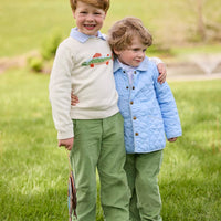 Little English traditional children's clothing. Boys cream crew neck sweater with fish motif layered over light blue striped polo and paired with watercress green corduroy pants. Little boy wearing light blue quilted jacket with watercress green corduroy pull on pants