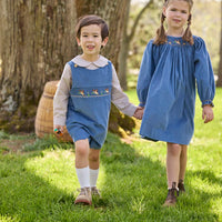 Little English traditional children's clothing. Khaki Gingham peter pan shirt for toddler boys paired with stormy blue corduroy shortall with flying mallard smocking across chest. Long sleeve stormy blue corduroy dress with flying mallard collar around the neckline for little girls.