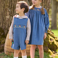 Little English traditional children's clothing. Khaki Gingham peter pan shirt for toddler boys paired with stormy blue corduroy shortall with flying mallard smocking across chest. Long sleeve stormy blue corduroy dress with flying mallard collar around the neckline for little girls.