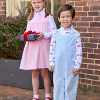 Little English classic children's clothing. White knit turtleneck with holiday train print layered under light blue corduroy Campbell Overall. White knit turtleneck with holiday present print layered under light pink corduroy Madison Jumper. Holiday outfit for little boys and girls.