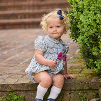 Little English classic children's clothing. Dressy peter pan bubble for baby girls in blue Wisteria Floral with puff sleeves, ruffle details, and smocking at chest.