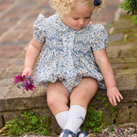 Little English classic children's clothing. Dressy peter pan bubble for baby girls in blue Wisteria Floral with puff sleeves, ruffle details, and smocking at chest.