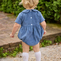 Little English classic children's clothing. Baby boys stormy blue corduroy peter pan bubble with button tabs and flying mallard smocking across the chest. White knee high socks with mallard embroidery.