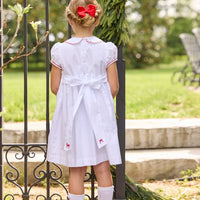 Little English traditional children's clothing. Puff sleeve white peter pan dress with scalloped collar, red trim, and bow smocking across the chest. Dressy outfit for little girls for the holiday