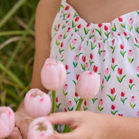 Little English traditional children's clothing.  White romper with red and pink tulip print and self-tie straps for little girls