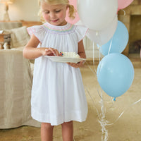 Little English traditional children's clothing. White flutter sleeve dress for toddler girls with rainbow smocking at the collar.  Birthday dress for little girls