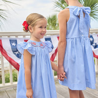 Little English traditional children's clothing. Flutter sleeve dress for toddler girls in royal blue mini gingham with smocking at the collar and American flag bunting
