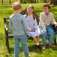 Little English traditional children's clothing.  Classic long sleeve peter pan shirt in blue Alpine Gingham paired with blue Alpine Corduroy pull on pants for toddler boys.  Older boys gray quarter zip sweater layered over blue Alpine Gingham button down shirt and paired with blue Alpine Corduroy classic pants. Ruffled collar long sleeve Bespoke Dress for little girls in blue and green Waterbury Floral