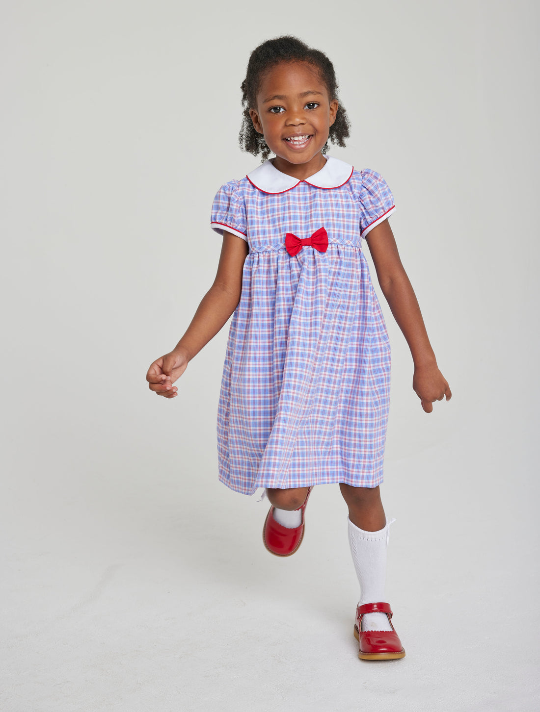 Little English toddler girl traditional red white and blue gingham woven dress with red and white piping