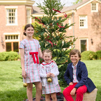 Little English classic children's clothing. Girls A-line Cora Dress in red and green plaid with red bow and red piping detail for the holidays.  Boys Douglas Plaid button down shirt with red corduroy pants and navy wool blazer. Toddler girls Eleanor Dress - Douglas Plaid with ruffled peter pan collar and tie sash in back paired with white Holiday Bow Fair Isle Cardigan