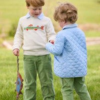 Little English traditional children's clothing.  Boys cream crew neck sweater with fish motif layered over light blue striped polo and paired with watercress green corduroy pants. Little boy wearing light blue quilted jacket with watercress green corduroy pull on pants