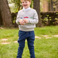Little English traditional children's clothing.  Grey intarsia sweater with 3 race cars layered over race car print turtleneck and paired with tapered navy sport pants for little boys.