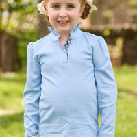 Little English traditional children's clothing.  Long sleeve Hastings polo in light blue with ruffle collar and green floral detailing. Paired with green floral leggings for little girls.  
