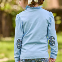 Little English traditional children's clothing.  Long sleeve Hastings polo in light blue with ruffle collar and green floral detailing. Paired with green floral leggings for little girls.  