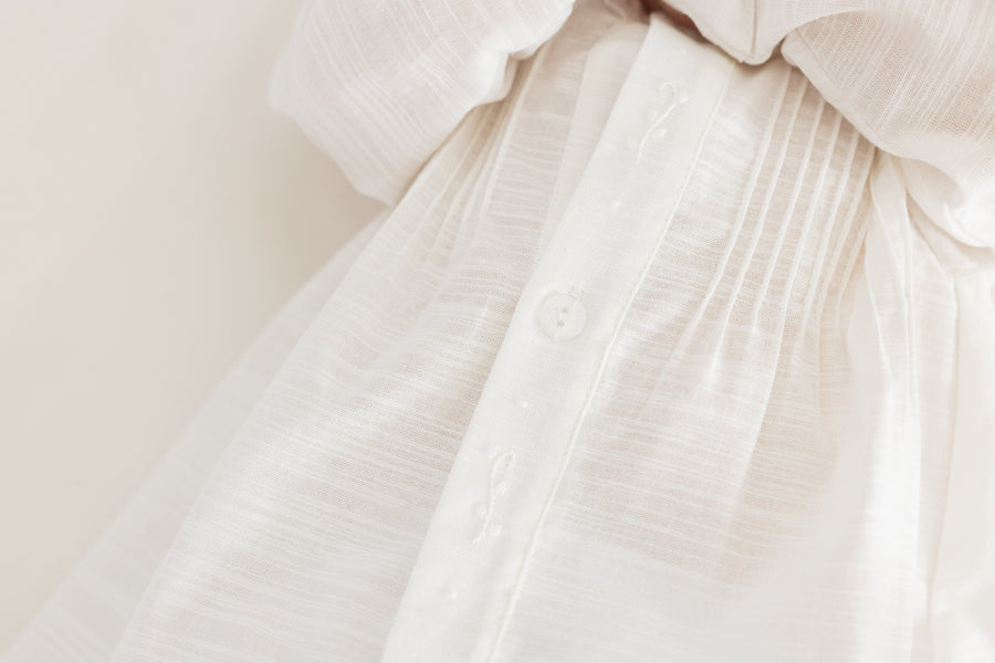 Little English traditional children's clothing.  Unisex pleated ivory newborn gown with ruffles and embroidered detailing at the collar and sleeves
