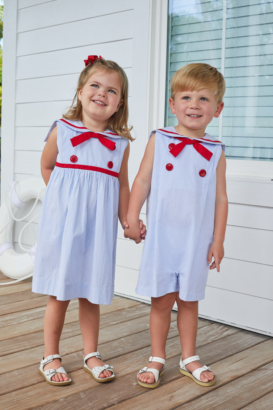 Little English traditional children's clothing, girl's classic thin light blue stripe dress with sailor collar, fixed neck tie, and red button detail for Summer
