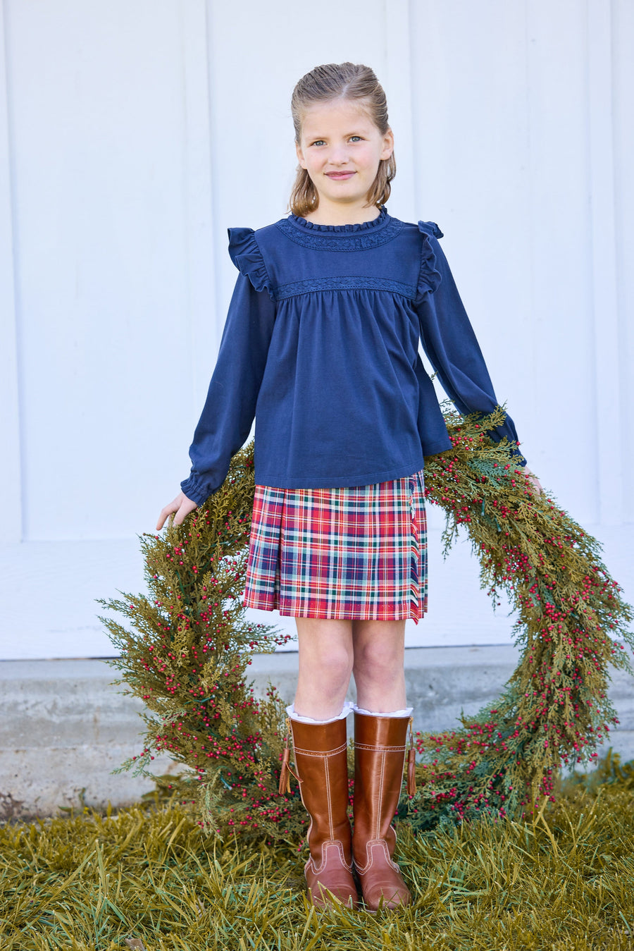 little english classic children's clothing girls navy long sleeve ruffle top with lace detailing a neck and chest, fringe skirt in deep red and navy middleburg plaid, fall outfit for girl