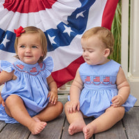 Little English traditional children's clothing.  Flutter sleeve bubble in royal blue mini check fabric and smocking with American flag bunting for baby girls