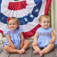 Little English traditional children's clothing.  Flutter sleeve bubble in royal blue mini check fabric and smocking with American flag bunting for baby girls