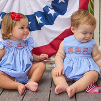 Little English traditional children's clothing.  Sleeveless bubble in royal blue mini check fabric and smocking at the chest with American flag bunting for baby boys