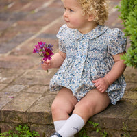 Little English classic children's clothing.  Dressy peter pan bubble for baby girls in blue Wisteria Floral with puff sleeves, ruffle details, and smocking at chest.
