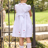 Little English traditional children's clothing.  Puff sleeve white peter pan dress with scalloped collar, red trim, and bow smocking across the chest.  Dressy outfit for little girls for the holiday