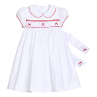 Little English traditional children's clothing.  Puff sleeve white peter pan dress with scalloped collar, red trim, and bow smocking across the chest.  Dressy outfit for little girls for the holiday