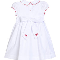 Little English traditional children's clothing.  Puff sleeve white peter pan dress with scalloped collar, red trim, and bow smocking across the chest.  Dressy outfit for little girls for the holiday