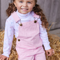 classic childrens clothing overall with brass buttons in a light pink twill